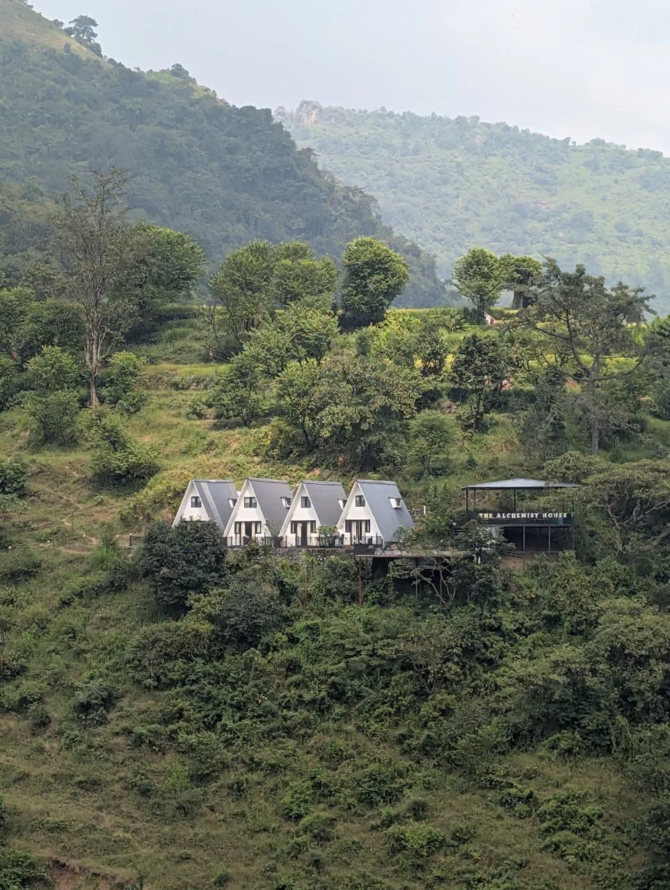 A row of white A-frame cottages tucked into a lush green hillside